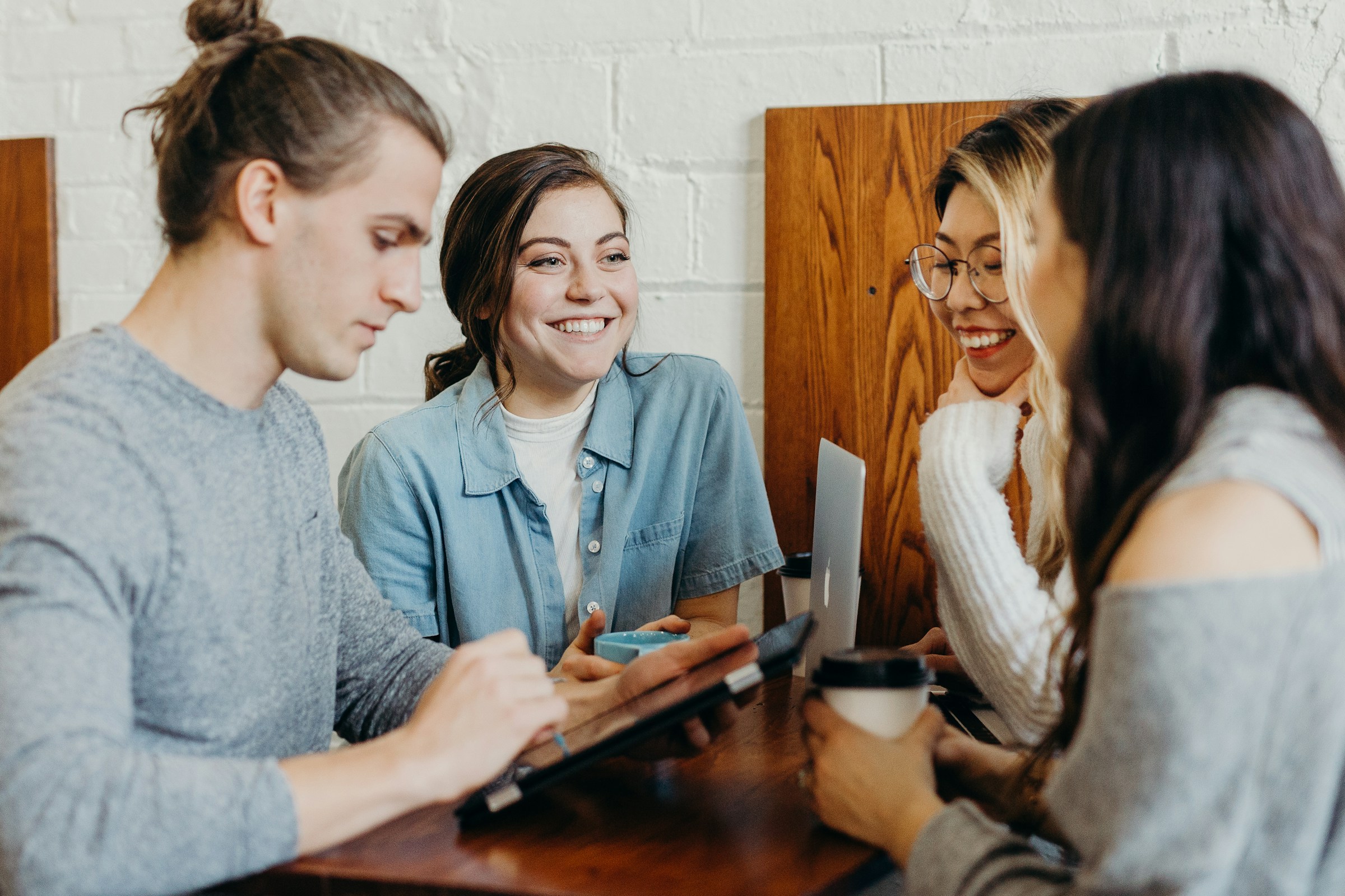 A small group of young adults sitting together at a table in conversation.